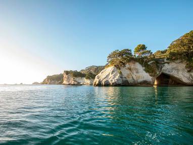Een kustlijn met oceaan en rotsen bij Cathedral Cove in Nieuw-Zeeland.