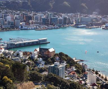 De stad en haven van Wellington aan de zee gelegen en omringd door hoge gebouwen.