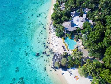 Het Pacific Resort Aitutaki vanaf boven gefotografeerd met de heldere oceaan en zwembad.